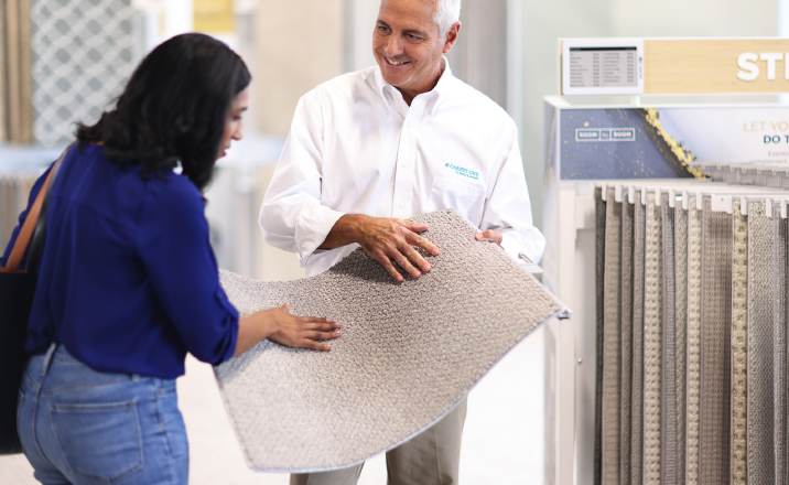 flooring expert showing carpet floor sample to customer